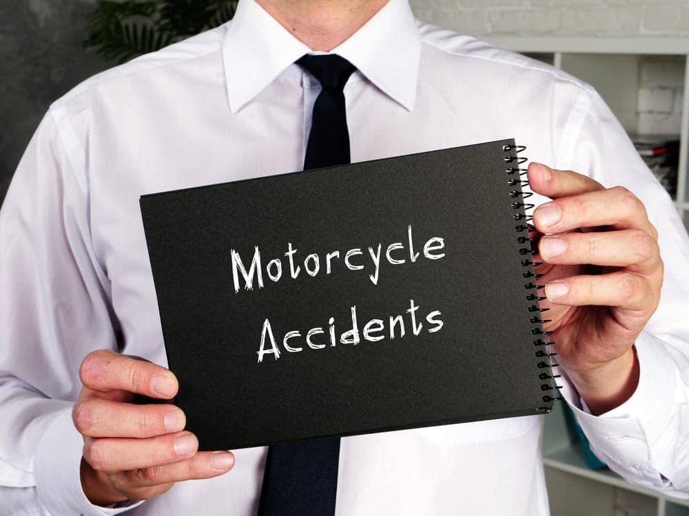 Una persona sostiene un cuaderno en el que está escrito "Accidentes de motocicleta", que representa los servicios de un abogado de Brooklyn especializado en accidentes de motocicleta.