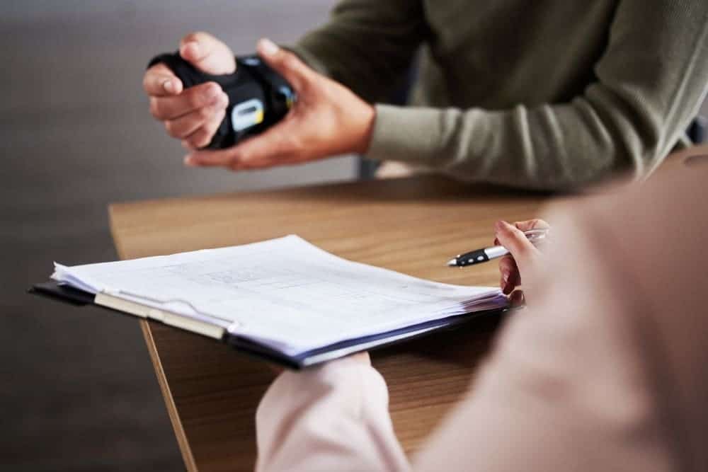 A workers' compensation lawyer in Brooklyn consulting with a client, holding documents and discussing a workplace injury claim.